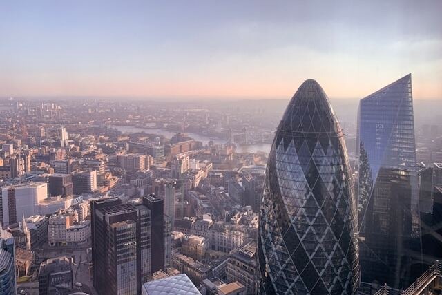 A morning aerial view across the London city skyline, with The Gherkin building in the foreground and the River Thames winding away in the background. Image at LondonOfficeSpace.com.
