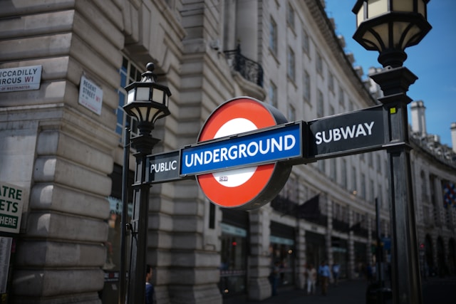 A close-up view of one of the London Underground signs affixed between two black light poles. Image at LondonOfficeSpace.com.