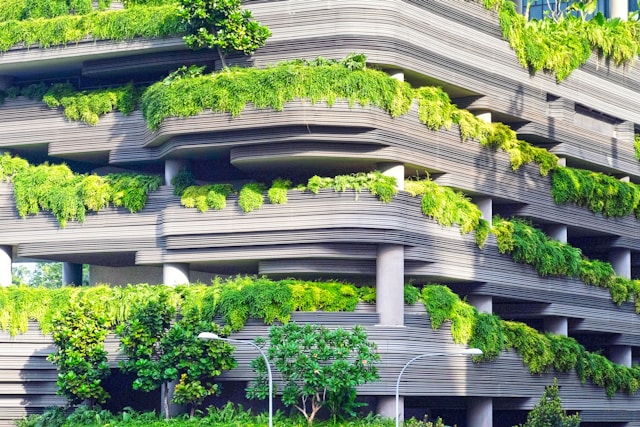 A front-on view of the grey, terraced facade of an office building. The spaces between the levels are filled with an abundance of plant life in many shades of green. Image at LondonOfficeSpace.com.