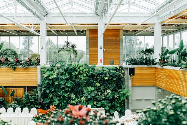 A view from within a commercial building’s interior green space. Sunlight streams down through the glass-panelled roof, and indoor plants fill wood-framed planters that line the interior walkways. Making good use of natural light and building materials, as well as providing green spaces for occupants, are great ways to increase a building’s BREEAM rating. Image at LondonOfficeSpace.com.